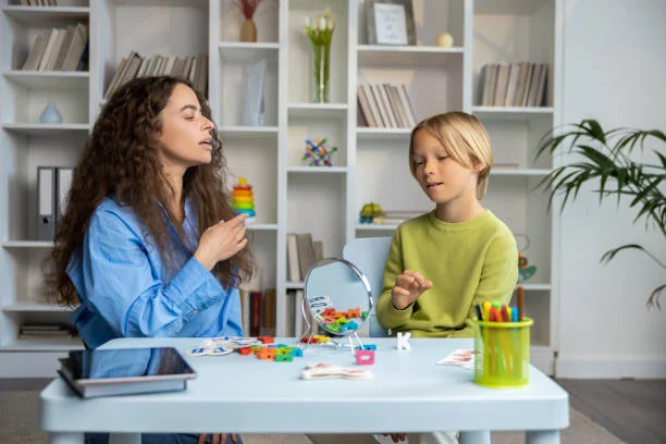 Speech exercises. Cute blonde boy having a session of speech exercises with speech therapist
