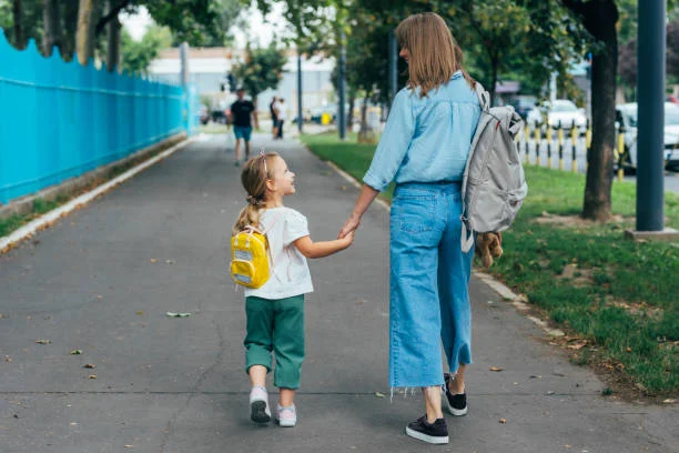 Anonymous Mother walking together with her daughter, holding her hand