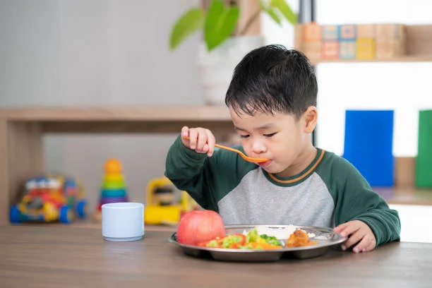 Asian student take a lunch in class room by food tray prepared by his preschool, this image can use for food, school, kid and education concept