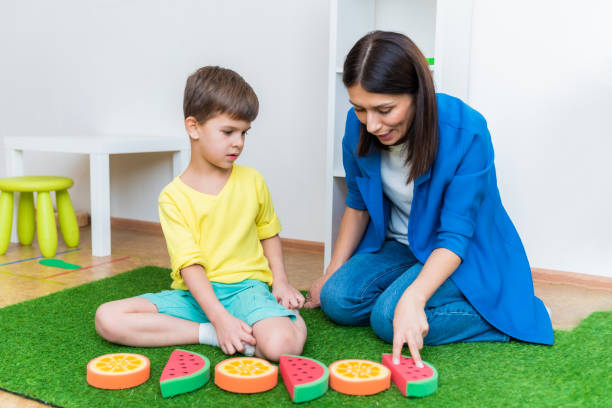 Woman speech therapist helps a boy correct the violation of his speech